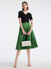 A lady wears a green skirt and a black top.